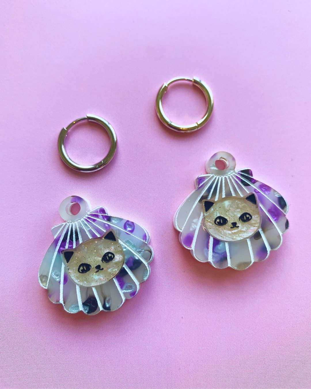 Cat Shell Huggie Earrings silver close up pink background